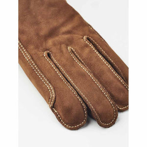 Men's brown nubuck leather gloves by Hestra, with contrasting white topstitching visible on the fingers and seams.