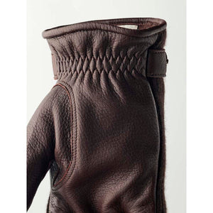 Dark brown elk leather glove by Hestra, with gathered wrist detail, a small strap, and visible cashmere lining.