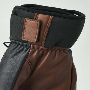 Brown and black leather 3-finger glove by Hestra with an adjustable wrist strap and black fabric cuff.