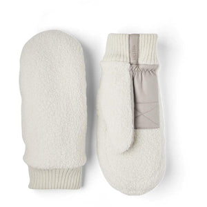 Cream fuzzy and leather mittens by Hestra with ribbed cuffs, featuring a light grey leather strap with the brand name.