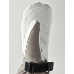 White leather women's mitt by Hestra, with grey fabric thumb and cuff, and a black adjustable wrist strap, cropped side view.