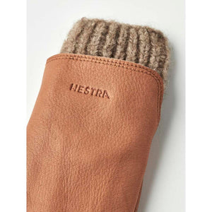 Brown deerskin glove by Hestra with a ribbed knitted cuff and embossed logo.