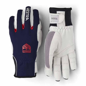 Navy and white ski gloves by Hestra, with red accents, a logo on the back, and a Gore-Tex Infinium wrist strap.