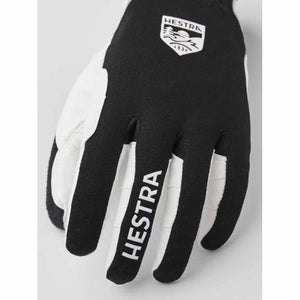 Close-up of a black and white ski glove by Hestra, featuring the brand logo on the back and 'HESTRA' text on the middle finger.