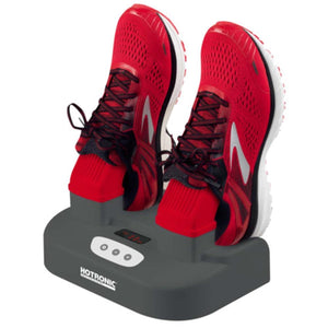 Dark gray dryer by Hotronic, with white control buttons and a red display, holding red running shoes and socks.