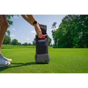 Dark grey soft cooler by Kanga Coolers, open with red cans visible, on a golf course.