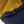 A two-toned mustard yellow and navy blue down sleeping bag by Kelty, partially open with a headlamp in an interior pocket.