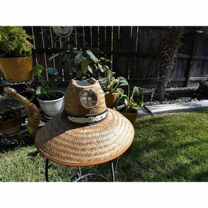 Men's straw Thurman Solar Fan Hat by Kool Breeze with a wide brim, integrated fan, and studded decorative band in a garden setting.