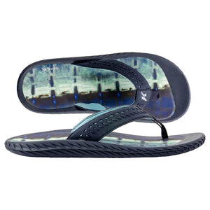 Dark blue flip-flops by Korkers, featuring a perforated strap, abstract blue-green insole, and textured outsole, one inverted.