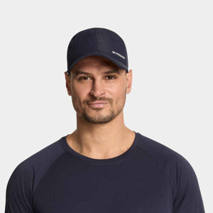 Dark blue performance hat by Mission, with a white 'M MISSION' logo and subtle pattern, on a man wearing a matching shirt.