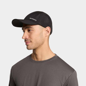 Black cooling performance hat by Mission with white logo, in side profile on a man wearing a grey t-shirt.
