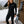 Black heated base layer shirt by Gobi Heat, with logo on chest and control buttons on hip and sleeve, worn by a woman in a snowy outdoor setting.