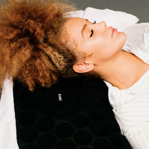 Black Cool Pad by Onyx Cool with textured circular patterns and 'ONYX' text, used by a person with curly hair wearing a white striped shirt.