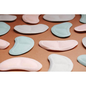 Assorted Gal Pals Chill Set by Opal Cool in light pink, blue, and white cushioned pads, scattered on brown.