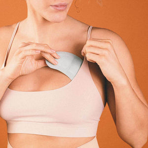 Light gray textured cooling pad by Opal Cool being inserted into a light pink sports bra.
