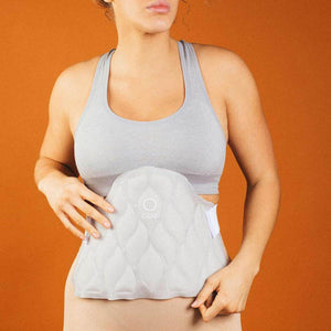 Light grey cooling pad by Opal Cool with quilted wavy pattern, a central circle and "opal" text, worn on a woman's abdomen.