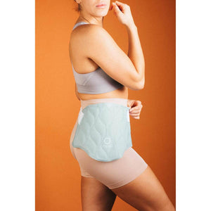 Light blue quilted cooling pad by Opal Cool with wavy pattern and logo, worn on a woman's lower back with white adjustable tabs.