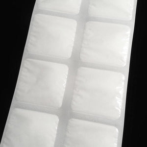 White square Cooling Paks for Gloves by Oro Sports, on a perforated sheet with slight wrinkles and rounded corners against a dark background.