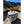 Grey cooler bag by Polar Bear Coolers, soft-sided with a top handle, on sand with boats and a river.