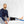 Black cold therapy knee compression pad by Polar Products, worn on a leg with a blue hose, a man sits next to it.