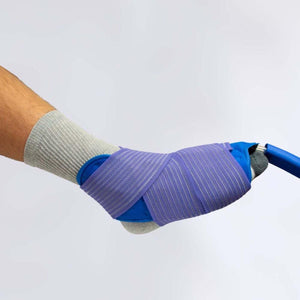 Universal U-shaped therapy pad in blue with a purple striped elastic wrap by Polar Products on a person's foot wearing a grey sock.