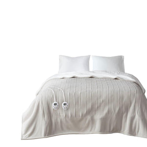 Light beige king-size heated fleece to sherpa blanket by Serta, with a ribbed texture and two attached controllers, draped over a bed with white pillows.