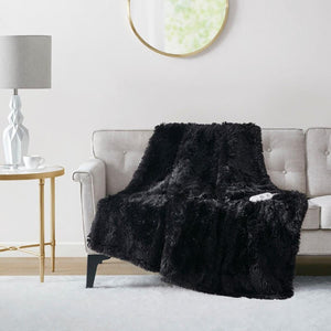 Black heated shaggy faux fur throw by Serta, draped on a light grey sofa with a white control unit visible.