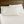 Cream sateen sheet set by Shavel on a neatly made bed with four matching pillows against a wooden headboard.
