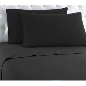 Black solid sheet set by Shavel, with two pillowcases on a bed with a white tufted headboard.