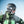 Matte black helmet by Smith Optics, side view, with white-strap goggles on a person wearing a green jacket.