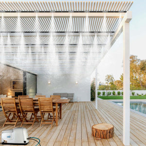 Patio misting system from The Patio Misting System, with a white pump and active nozzles under a pergola.