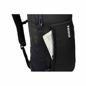 Black laptop backpack by Thule, cropped view showing a main zipper and a side pocket holding a white ticket.
