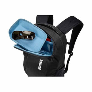 Black laptop backpack by Thule, open showing a blue-lined compartment with sunglasses and padded shoulder straps.