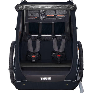 Black 2-seat bike trailer by Thule, featuring two gray padded harnesses and a clear weather cover from an interior view.