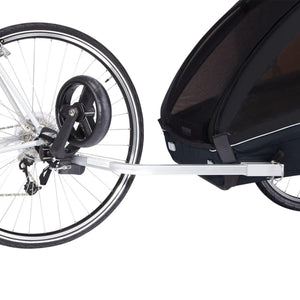 Black 2-seat bike trailer by Thule, attached to a bicycle's rear wheel with a silver hitch arm.