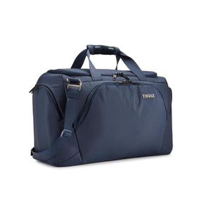 Dark blue duffel bag by Thule made of textured fabric, with top handles and a shoulder strap, angled view.