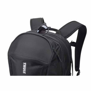 Black laptop backpack by Thule with white logo, featuring padded straps and sunglasses resting on top.