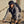 Black backpack from Thule worn by a man riding a bicycle in a grey hoodie.