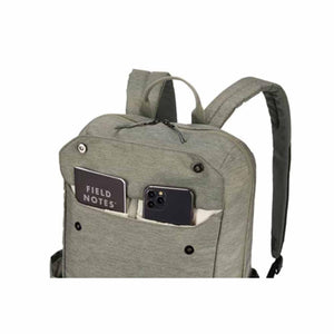 Muted green laptop backpack by Thule, cropped front view, with a front pocket holding a notebook and smartphone.