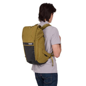 Olive green and black backpack by Thule featuring a black front panel with logo, worn on the back by a person.