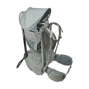 Light green baby hiking backpack by Thule, featuring an extended sunshade, padded straps, and a sturdy kickstand.