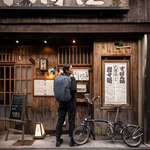 Slate grey 27L backpack by Thule, worn by a woman looking towards a traditional Japanese shop.