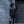 Dark grey crossbody bag by Thule, held by a woman wearing a black jacket, outdoors.