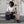 Black roll-top backpack by Thule, sitting on stone steps beside a woman in a beige top.