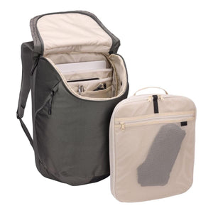 Charcoal travel backpack by Thule, open to reveal internal compartments, alongside a light beige mesh packing cube.