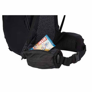 Black 30L backpack by Thule with a mesh back panel and hip belt pocket holding a snack bar, cropped.