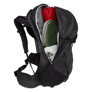 Black 30L backpack by Thule featuring mesh straps and an open main compartment revealing a red bag, green container, and white towel.