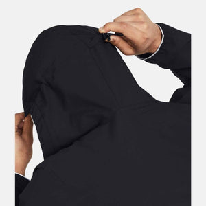 Black hooded jacket by Under Armour, shown from the back with hands tightening the hood's drawcord toggle.