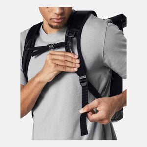 Black small backpack by Under Armour, worn by a man in a grey t-shirt adjusting a numbered strap marked "Leveled".