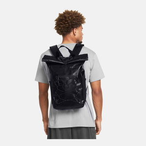 Black textured roll-top Summit Small Backpack by Under Armour with front bungee cords, worn on a person's back.